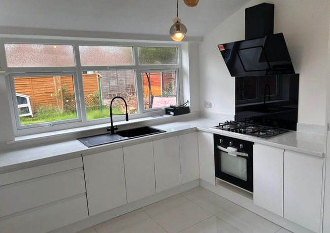 Modern kitchen with white cabinets, black appliances, including a sleek oven and stovetop
