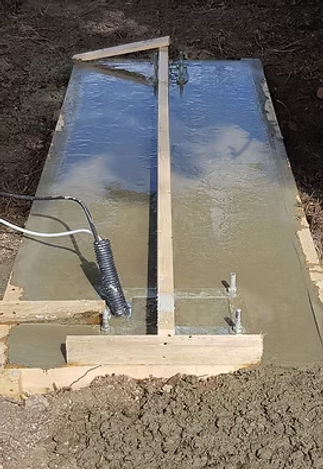 Wet concrete slab with wooden borders and embedded metal rods and wires