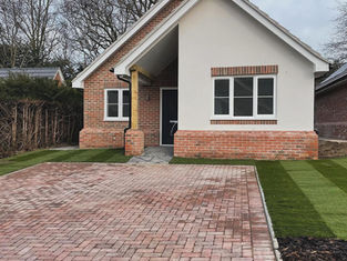Finished white rendered bungalow with a block-paved driveway and lawn