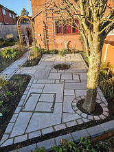 A neatly designed garden path with geometric paving stones, encircling a tree