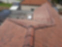 Aerial view of red tiled roof with ridges and skylight, yard hints at suburban setting