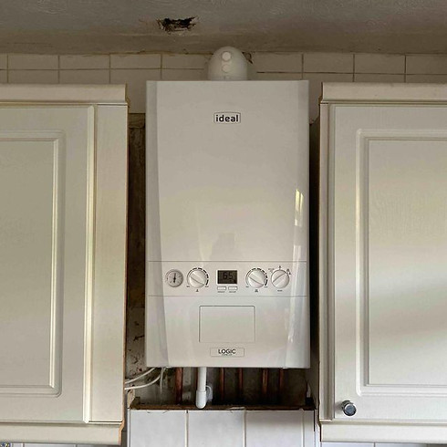 White 'Ideal Logic' boiler between cream kitchen cupboards