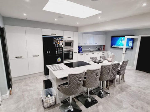 Sleek modern kitchen with white cabinetry, center island, and gray cushioned bar stools