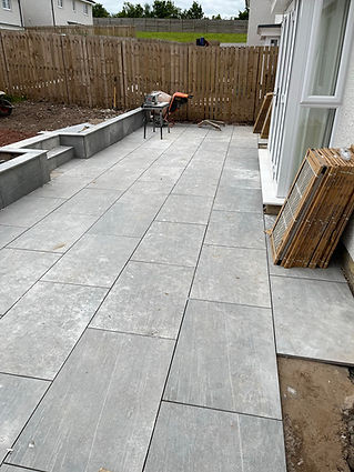 A newly paved gray patio with large tiles is adjacent to a white building