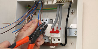 An electrician connecting wires to a fuse board