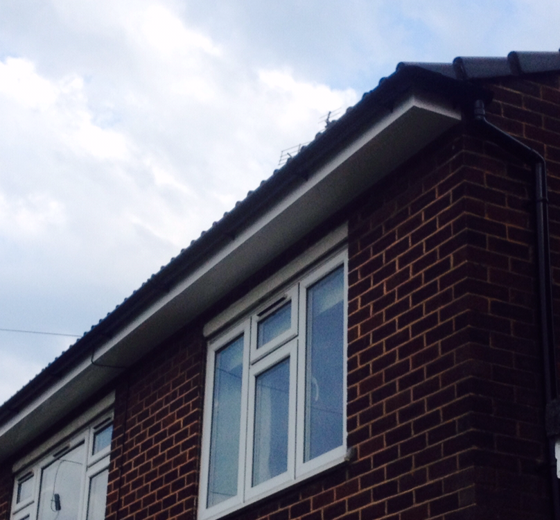 Brick house corner with white-framed window under a slanted roof