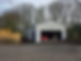 Completed standalone steel garage with light grey cladding and a red car parked inside