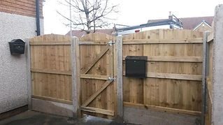 Wooden fence with a central gate, secure metal latch, and a black mailbox attached