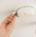 Hand changes battery in fire alarm on ceiling, highlighting safety