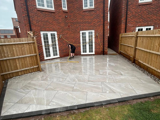 Two identical brick houses with white-framed windows and doors are separated by a wooden fence