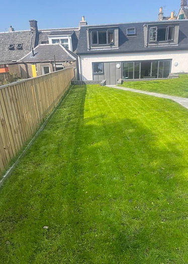 A lush, neatly mowed lawn bordered by a wooden fence on the left