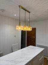 A modern kitchen with three glowing pendant lights over a white marble island