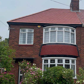 A two-story brick house with red roof and white-framed windows