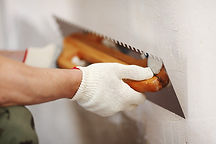 Gloved hand applying plaster to a wall