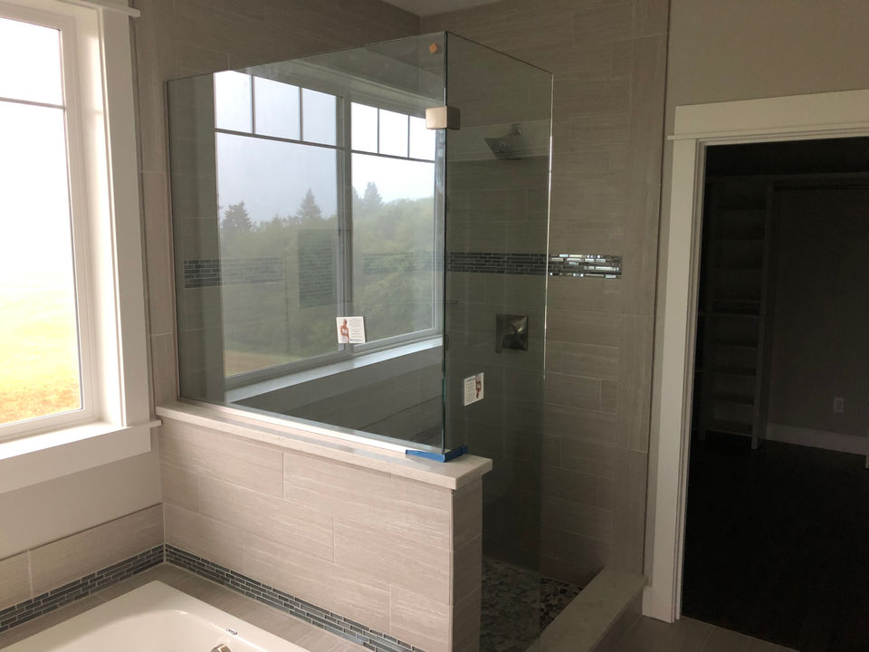 Glass shower enclosure with window, gray tile, modern home bathroom.