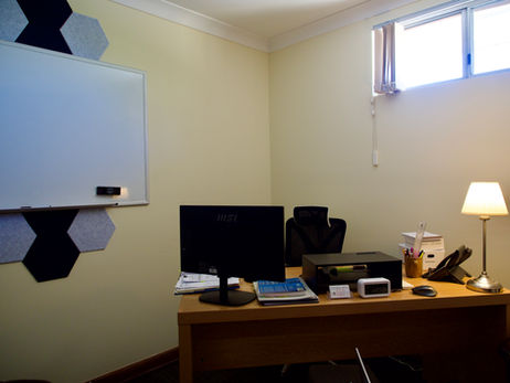 Another office desk with monitor, printer, and lamp. Room with white board in corner, ready to visually assist during sessions, here at the Bruce Psychology clinic in Mandurah.