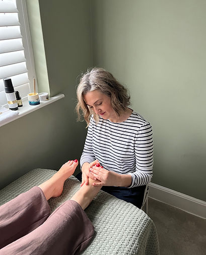 Sarah doing a foot reflexology treatment on female client.