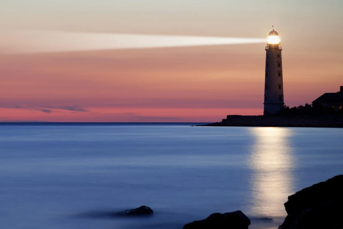 Lighthouse-shining-light-over-water.jpg.webp