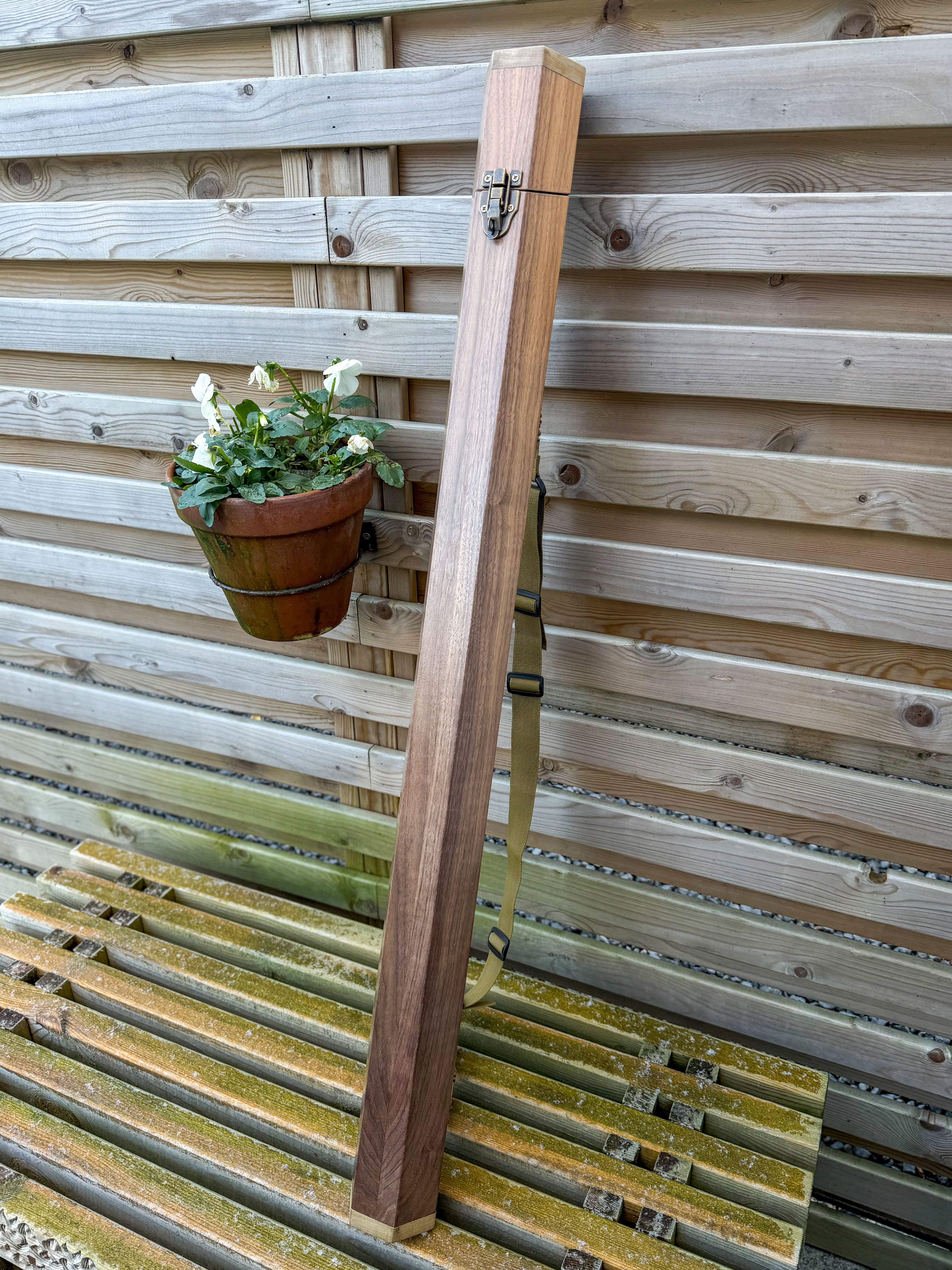 beautiful oak walnut handmade fly fishing rod tube case with a wooden back ground on a wooden bench uk made