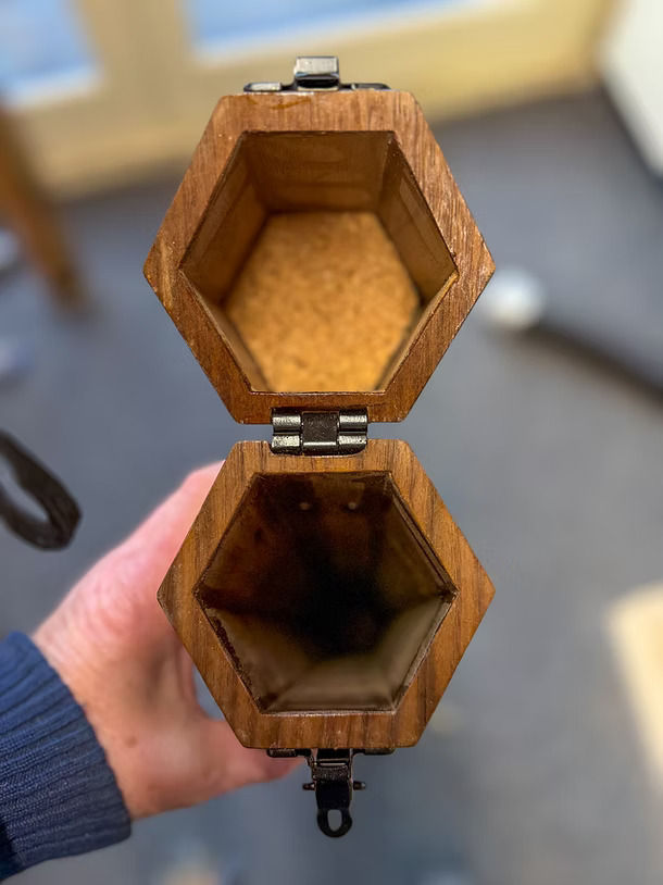 Thumbnail: beautiful oak walnut handmade fly fishing rod tube case with a wooden back ground on a wooden bench with a plant hanging