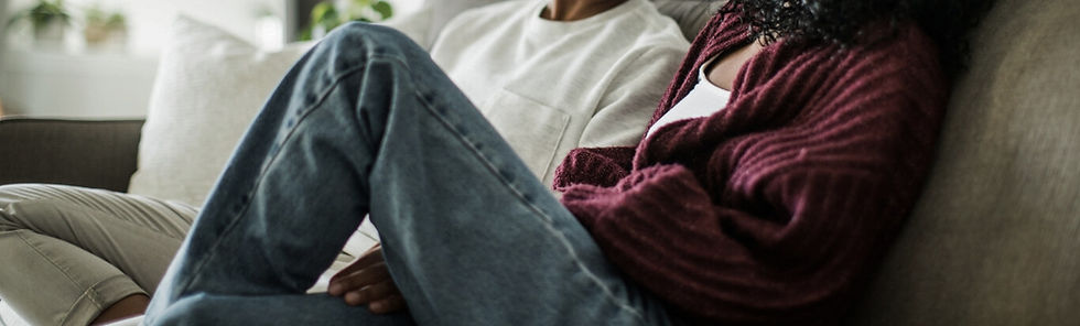 Deux femmes assises côte à côte sur un canapé, dans un cadre intime et chaleureux. L'une porte un pull bordeaux, l'autre un chandail blanc. Leur posture suggère un moment de dialogue ou de résolution de conflit, dans une atmosphère calme et bienveillante.