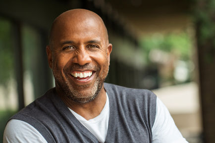 A bald black man with a trimmed short beard smiling