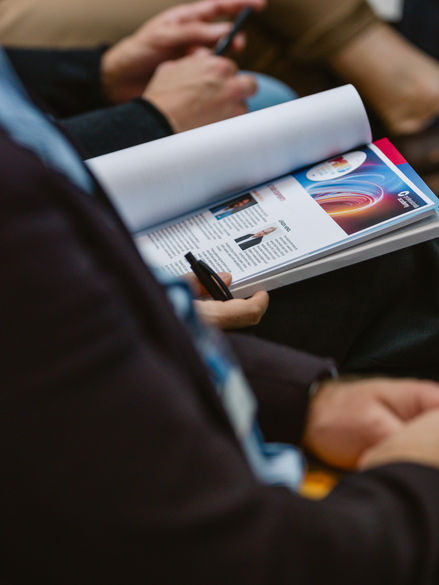 Sitzende Kongressteilnehmer mit aufgeschlagenem Programm