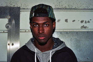 Young man wearing a cap and hoodie, staring intently, DaMarcus J. Nelson.