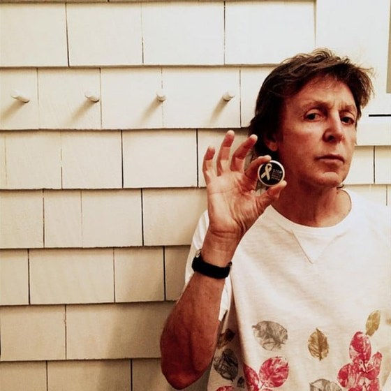 Paul McCartney holding a White Ribbon campaign token