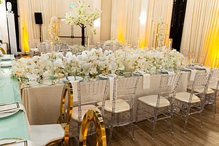 Wedding reception tables with white floral centerpieces and amber uplighting on the drapes at Aristide McKinney