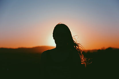 Frau schaut in den Sonnenuntergang - Symbol für Schattenarbeit, Heilung