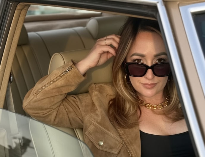 Ai Naomi sits in car wearing sunglasses