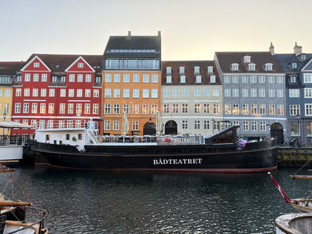 Colorful buildings of Nyhavn with a long boat on the water in the foreground