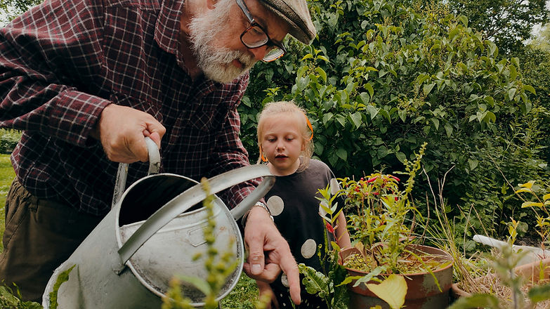 Une personne âgée qui jardine avec une petite fille. 