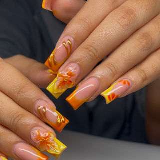 Medium square acrylics with ombré orange and yellow French tips, gold swirls, 3D hibiscus flowers, and subtle petal accents.