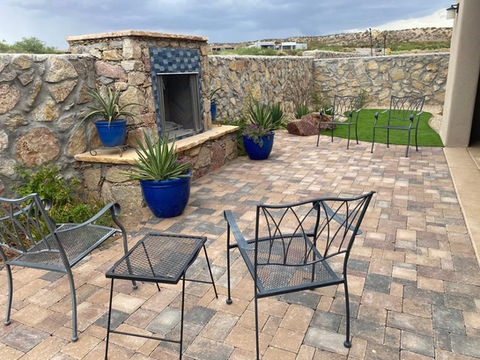 Patio with interlocking pavers, stone fireplace, and seating area, available at Garden Center.