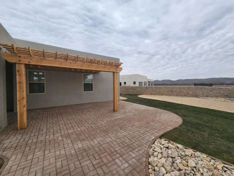 Backyard pergola and paver patio with turf and decorative stone edging in Las Cruces, NM by Garden Center.