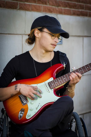 [image description]: yannick-robin sits in jasper, while playing a bright red Fender strat.