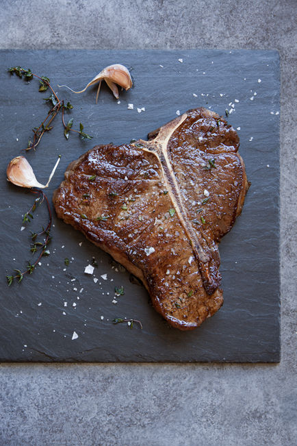 Grilled steak on slate with garlic and herbs.