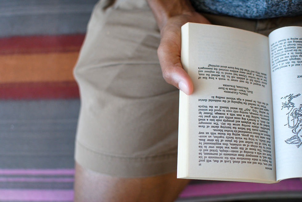 Visão de cima de uma pessoa sentada, com um livro aberto em suas mãos