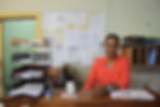 A doctor sitting at her desk doing some paper work smiling at the camera