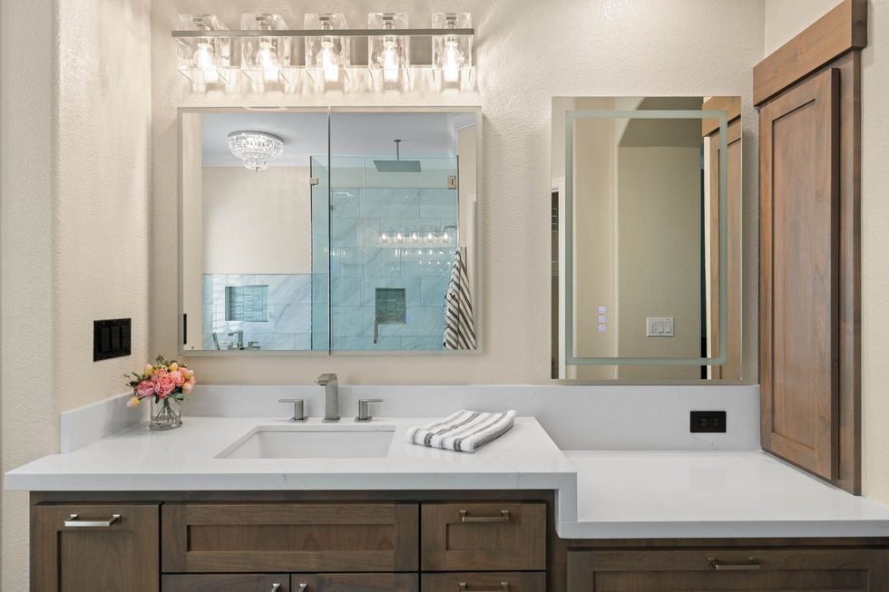 Double vanity with alder cabinetry, quartz countertops, framed mirrors, and contemporary lighting.