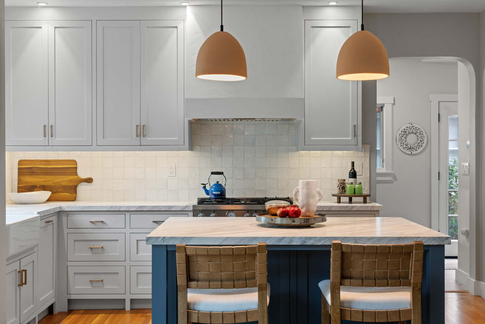 Bright kitchen with custom flush-inset shaker cabinets, a blue island with furniture-style legs, quartz countertops, and brass hardware under modern pendant lights.