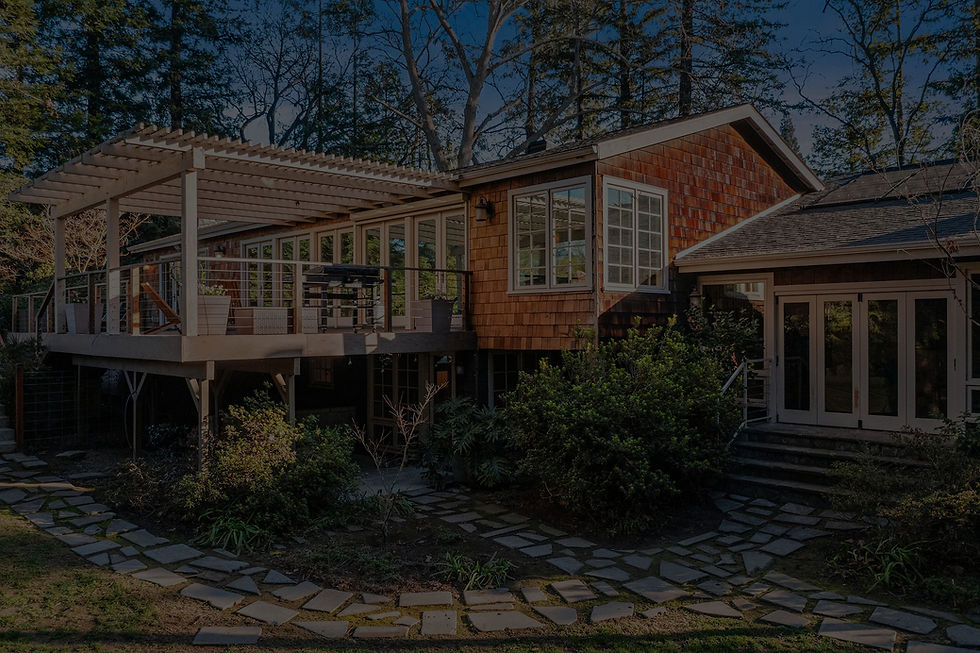 Modern home exterior with glass sunroom addition, white pergola deck, and stone path throu