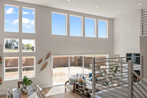 Sunlit living room with tall stacked windows and neutral modern décor.