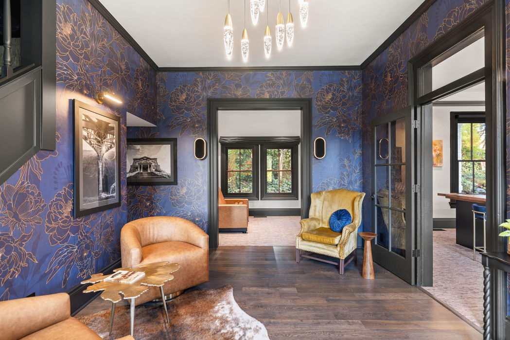 Meeting room in Auburn historic remodel with custom walnut table, modern chairs, and deep blue patterned walls framed by black-trimmed windows.