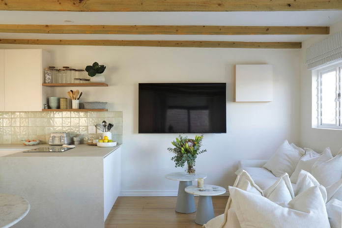 Modern open-plan living area with kitchen, TV, and white couch
