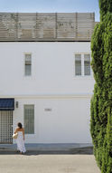 Woman in white dress by a white building and tall green tree