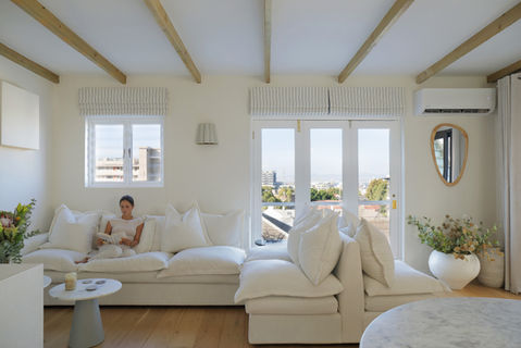 Woman relaxing on a white sectional sofa in a bright living room