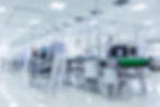 A cleanroom factory with workers in white protective suits working in laboratory